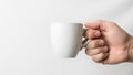 A hand holds a plain white ceramic mug against a neutral background Royalty Free Stock Photo