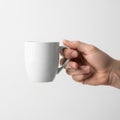 A hand holds a plain white ceramic mug against a neutral background Royalty Free Stock Photo
