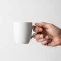 A hand holds a plain white ceramic mug against a neutral background Royalty Free Stock Photo