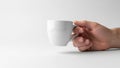 A hand holds a plain white ceramic mug against a simple light gray Royalty Free Stock Photo