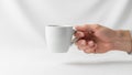A hand holds a plain white ceramic mug against a solid white background Royalty Free Stock Photo