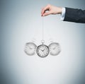 A hand holds a pocket watch in a chain as a pendulum. Light blue background. Royalty Free Stock Photo