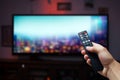 Hand holds a remote, altering channels on an empty TV screen Royalty Free Stock Photo