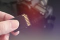 Hand holds SD Card against DSLR camera Royalty Free Stock Photo