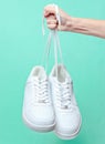 The hand holds by shoelaces hipster white sneakers Royalty Free Stock Photo