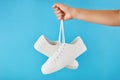 The hand holds by shoelaces Pair of fashion stylish white sneakers on pastel blue background Royalty Free Stock Photo
