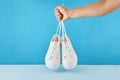 The hand holds by shoelaces Pair of fashion stylish white sneakers on pastel blue background Royalty Free Stock Photo