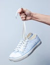 The hand holds by shoelaces retro style hipstel sneakers Royalty Free Stock Photo