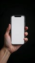 Hand holding a modern smartphone with a blank white screen against a dark background Royalty Free Stock Photo