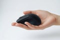 Hand holds small wireless black computer mouse. Modern tech item. Simple studio shot on white backdrop. Useful for tech product Royalty Free Stock Photo