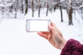 Hand holds smartphone with cutout screen in winter