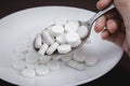 The hand holds a spoon over a plate filled with pills. Tablet overdose concept. The use of food additives Royalty Free Stock Photo