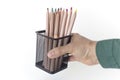 a hand holds a stationery glass with multi-colored pencils