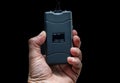 Hand holds a stun gun in front of black background Royalty Free Stock Photo