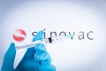 A hand holds a syringe in front of Sinovac vaccine logo in Barcelona, Spain, on May 18, 2021. Sinovac Biotech Ltd is a chinese