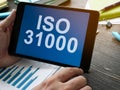 Hand holds tablet with data about ISO 31000. Royalty Free Stock Photo