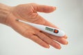 A hand holds a thermometer. Fever as a sign of Coronovirus Covid-19