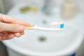 Hand holds a toothbrush with toothpaste on bathroom background, close up view. Royalty Free Stock Photo