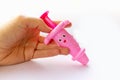 Hand holds toy baby pink syringe on white background Royalty Free Stock Photo