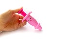 Hand holds toy baby pink syringe on white background. Royalty Free Stock Photo