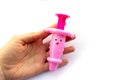 Hand holds toy baby pink syringe on white background. Royalty Free Stock Photo