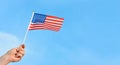 Hand holds USA flag on blue sky background.American symbol of Independence Day, Fourth of July, democracy and patriotism. Copy Royalty Free Stock Photo