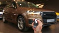 Hand holds and using remote key to unlock a car. Turn signals blinking. Brand New Car. SUV. Allroad