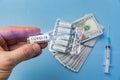 Hand holds vial of vaccine coronavirus on background of money and syringe. Price of drugs from covid-19, concept Royalty Free Stock Photo