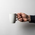 A hand holds a white ceramic mug against a plain white background. The hand is positioned on the Royalty Free Stock Photo