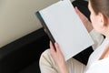 Beautiful female hands hold an open book or magazine in a room on a black sofa Royalty Free Stock Photo