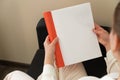 Beautiful female hands hold an open book or magazine in a room on a black sofa Royalty Free Stock Photo