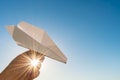 Hand holds white paper plane on sky and sun Royalty Free Stock Photo