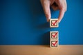 Hand holds a wooden block with a red checkmark on a blue background