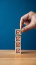 Hand holds a wooden block with a red checkmark on a blue background