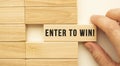 Hand holds a wooden cube with the text ENTER TO WIN