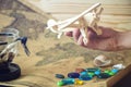 Hand holds wooden toy plane on a world map with colored stones and shells from the sea in a retro style Royalty Free Stock Photo