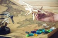 Hand holds wooden toy plane on a world map with colored stones and shells from the sea in a retro style Royalty Free Stock Photo