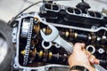 Hand holds a wrench on the background of the engine being repaired