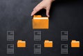 A hand holds a yellow folder over a black background with several folders and documents scattered around. Concept of control and