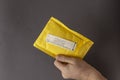 A hand holds a yellow mail package with the words RETURN TO SENDER