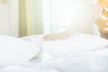 Hand of housekeeper set up white pillow on the bed sheet in hotel room at morning time with sunlight from windows Royalty Free Stock Photo