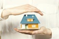 Hand hovering small family house, home insurance concept