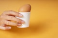 Hand of human holding Boiled organic chicken egg in ceramic cup or holder