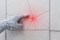 Hand of industrial worker in construction glove points finger on damaged tile floor background. Renovation concept