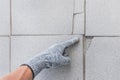 Hand of industrial worker in construction glove points finger on damaged tile floor background. Renovation concept
