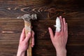 Hand with injured finger is holding a hammer on dark wooden. background Royalty Free Stock Photo