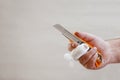 Hand with injured finger wrapped with gauze bandage holding knife