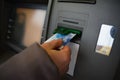 Hand inserting ATM card into bank machine to withdraw money