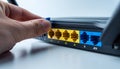 Hand inserting blue ethernet cable into yellow network router port Royalty Free Stock Photo