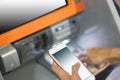 Hand inserting a credit card in an atm holding smart phone Royalty Free Stock Photo